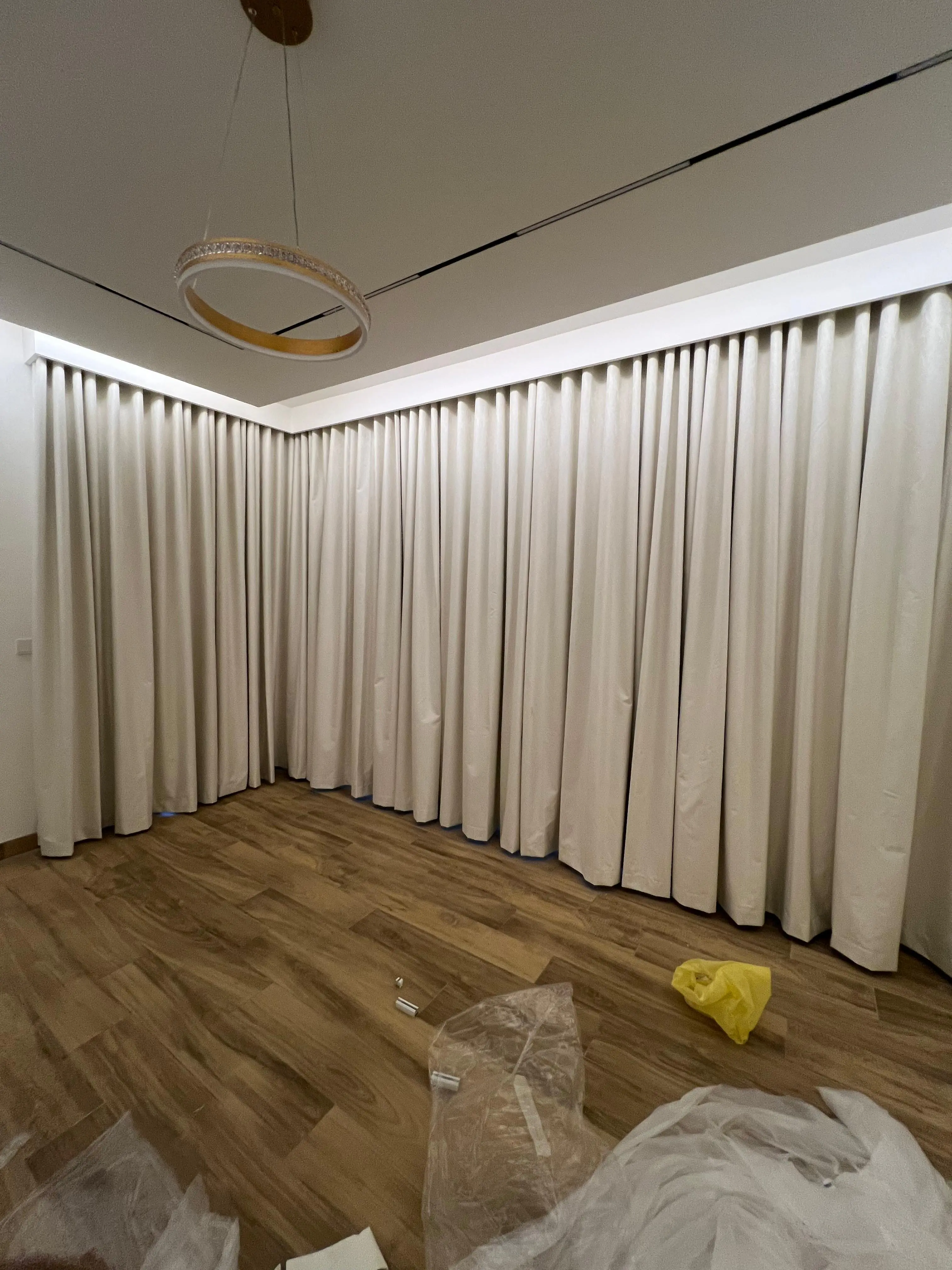 Cover entire wall with curtains across a wide living room in Dubai using ceiling tracks and layered drapes