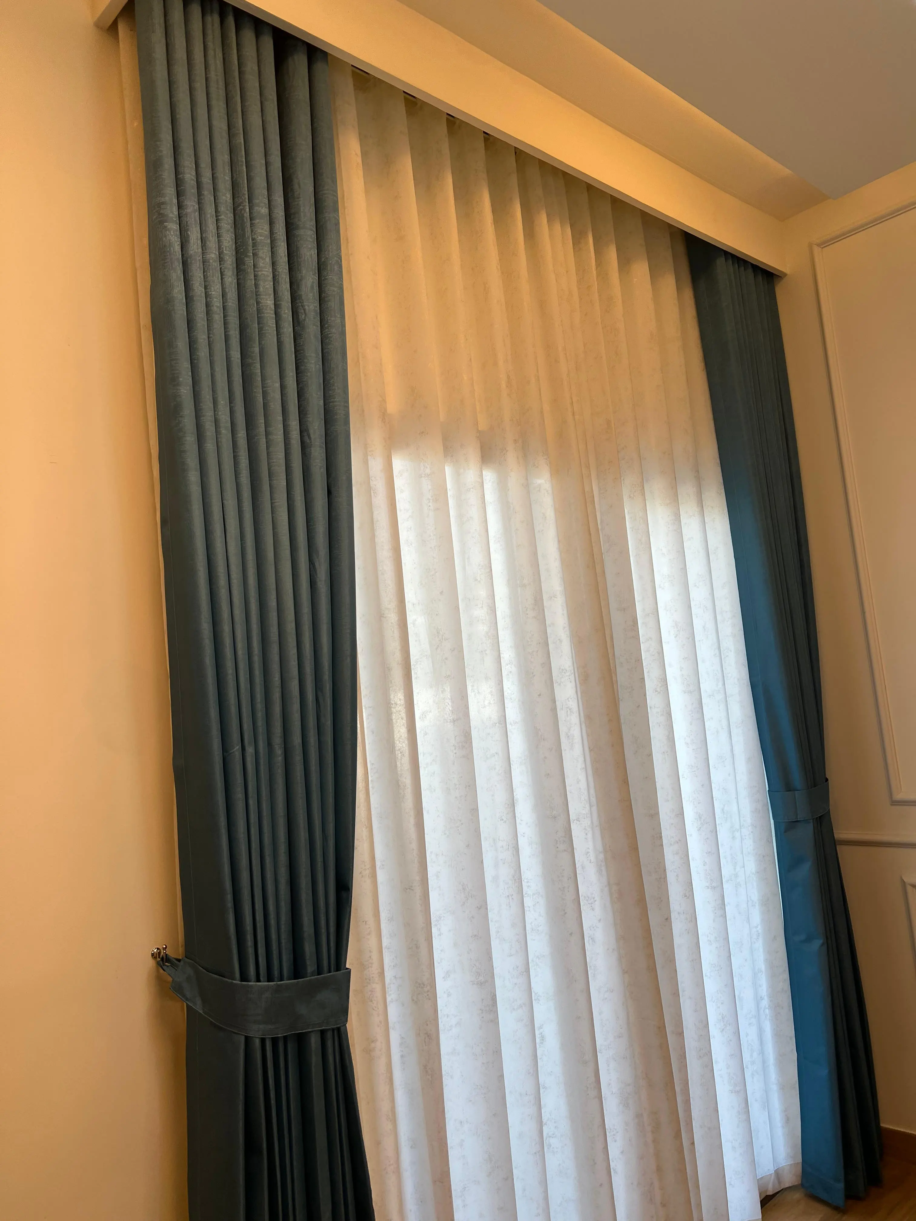 Matching curtains with wall color in a Dubai living room, soft greige walls with pearl drapes